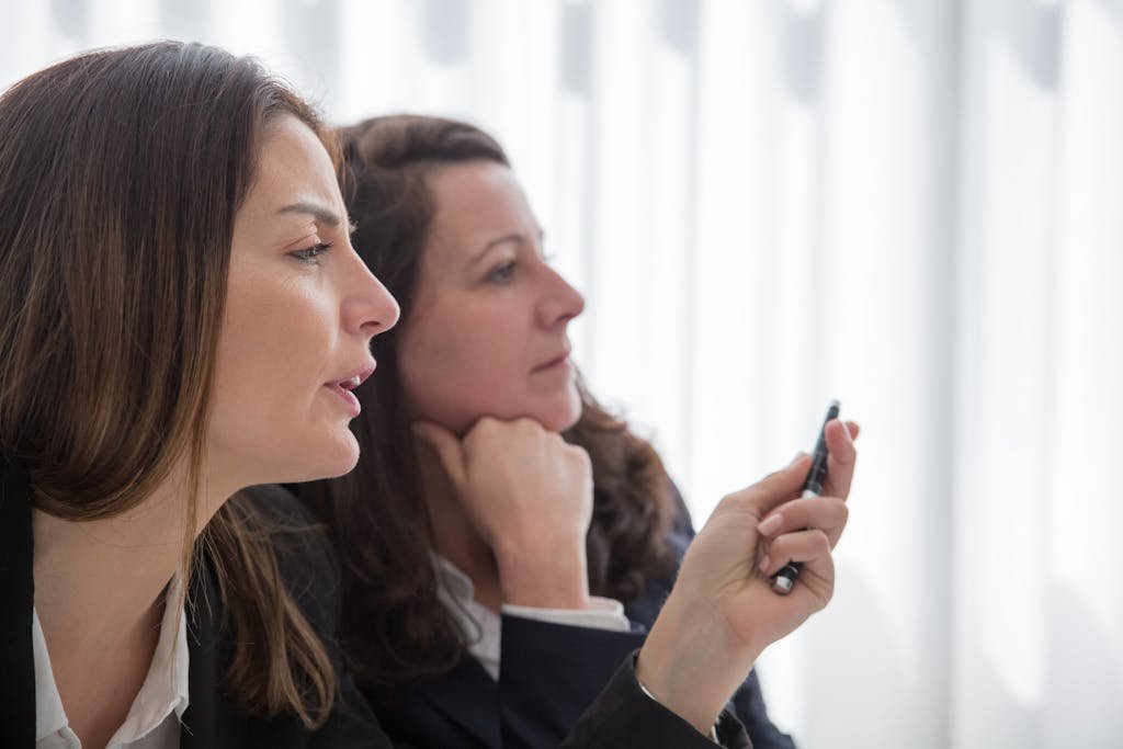 Close-up of two women colleagues discussing ideas thoughtfully in a modern office setting.